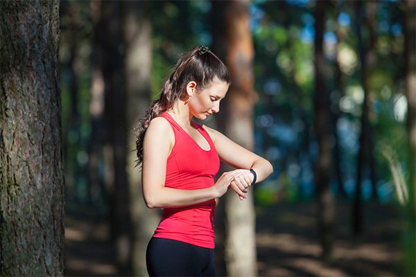 A woman checking her fitness tracker in the woods